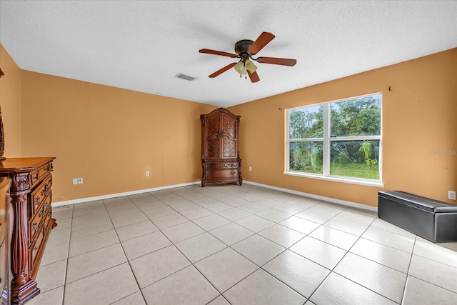 unfurnished living room with light tile patterned flooring, ceiling fan, and a textured ceiling