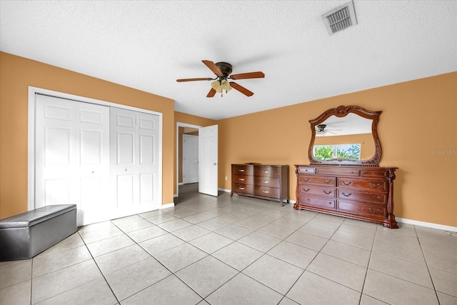 bedroom with light tile patterned flooring, ceiling fan, a closet, and a textured ceiling