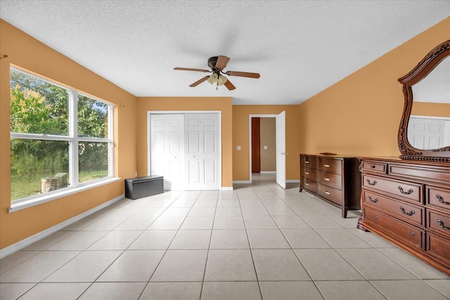 unfurnished bedroom featuring ceiling fan, a closet, a textured ceiling, and light tile patterned floors