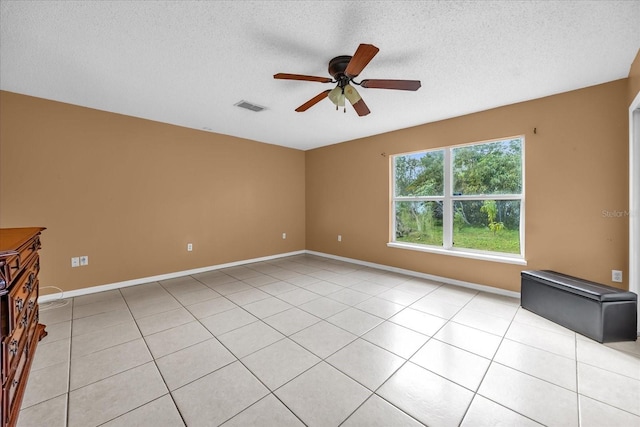 spare room featuring ceiling fan, light tile patterned floors, and a textured ceiling