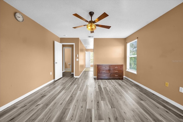 unfurnished bedroom featuring ceiling fan, light hardwood / wood-style floors, and a textured ceiling