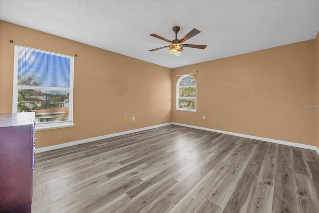 unfurnished room with ceiling fan, a textured ceiling, and light wood-type flooring