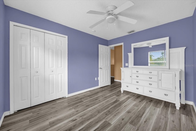 unfurnished bedroom featuring ceiling fan, light hardwood / wood-style floors, and a closet