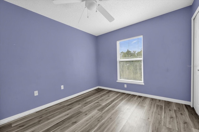 spare room with ceiling fan, a textured ceiling, and light wood-type flooring