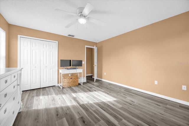 unfurnished bedroom featuring light hardwood / wood-style floors, a closet, and ceiling fan