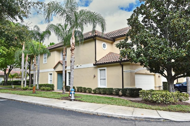 view of front of home with a garage, a tile roof, and stucco siding