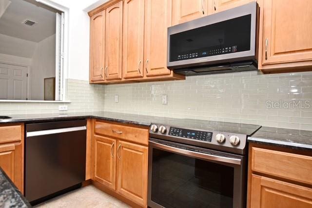 8766 The Esplanade Unit 23, Orlando, FL 32836 - kitchen featuring dark stone counters, visible vents, stainless steel appliances, and tasteful backsplash