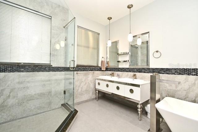 8766 The Esplanade Unit 23, Orlando, FL 32836 - bathroom featuring double vanity, a freestanding tub, tile walls, and a shower stall