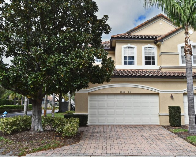 8766 The Esplanade Unit 23, Orlando, FL 32836 - mediterranean / spanish house with a tiled roof, decorative driveway, a garage, and stucco siding