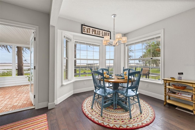 dining area featuring dark wood-style floors, a chandelier, and baseboards