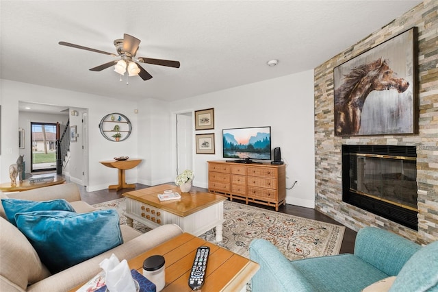 living room featuring a fireplace, wood finished floors, a ceiling fan, and baseboards