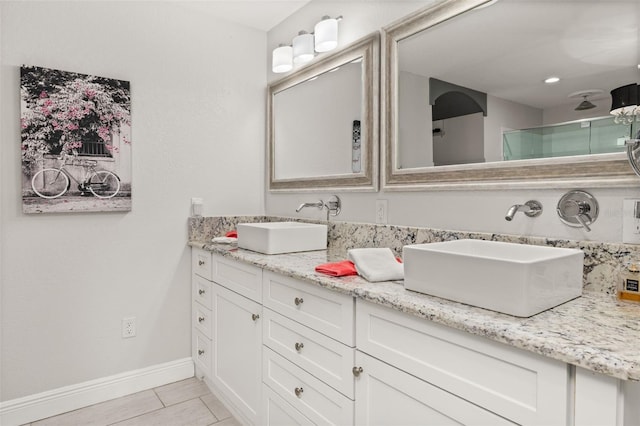 full bath featuring tile patterned flooring, a sink, baseboards, and double vanity