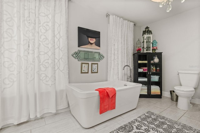 full bath with a freestanding bath, a notable chandelier, and baseboards