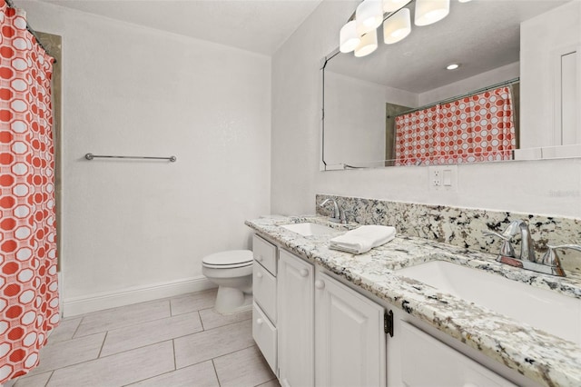 full bathroom featuring toilet, double vanity, baseboards, and a sink