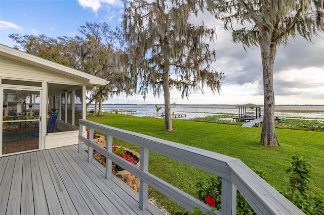 wooden deck with a yard, a water view, and a sunroom