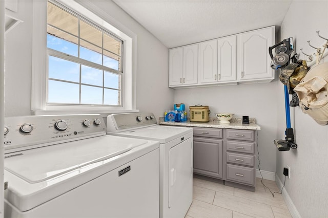 washroom featuring cabinet space, light tile patterned floors, baseboards, a textured ceiling, and washing machine and dryer