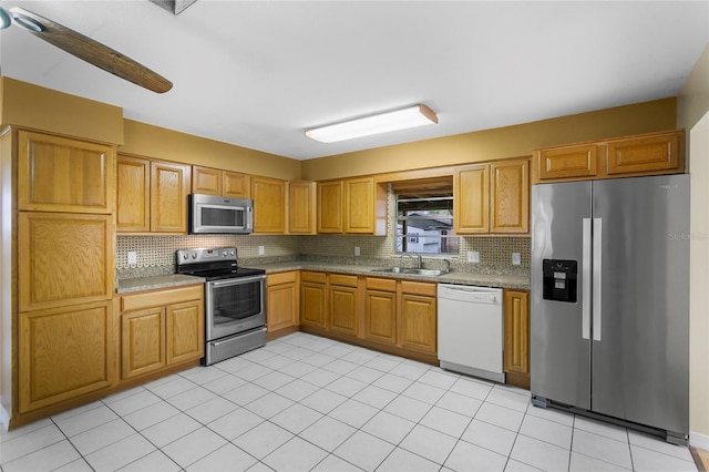 kitchen with sink, backsplash, light tile patterned floors, stainless steel appliances, and light stone countertops