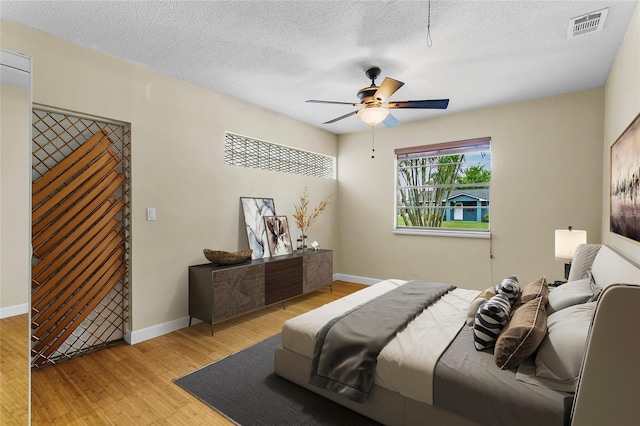 bedroom featuring ceiling fan, a textured ceiling, and light wood-type flooring