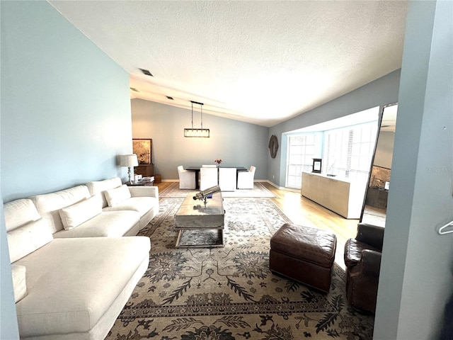 living room with a textured ceiling, lofted ceiling, and light hardwood / wood-style floors