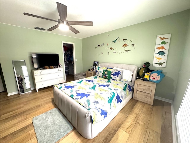 bedroom featuring ceiling fan, a spacious closet, a closet, and hardwood / wood-style floors