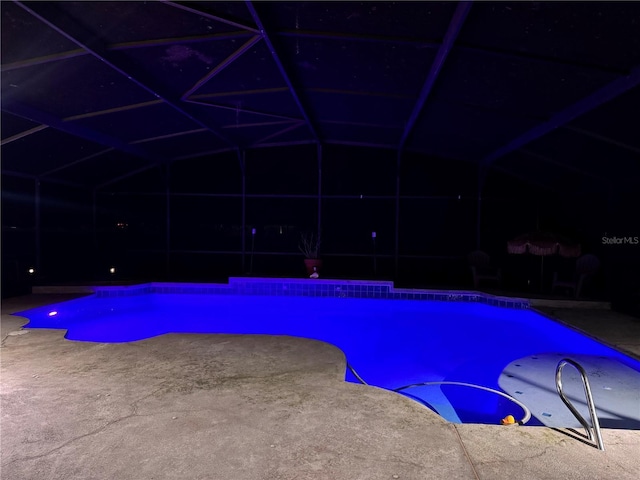 pool at twilight featuring a lanai and a patio area