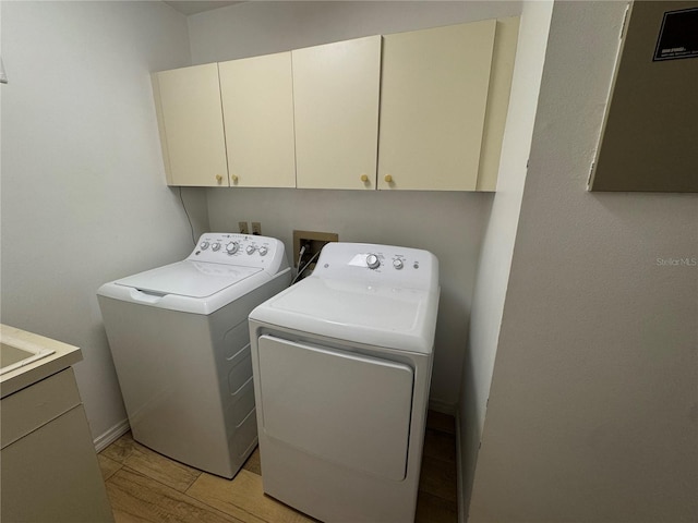 laundry room with cabinets, light hardwood / wood-style flooring, and washing machine and clothes dryer