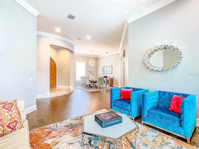 living room with an inviting chandelier, arched walkways, wood finished floors, visible vents, and ornamental molding