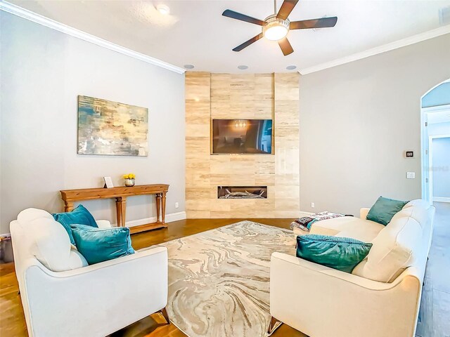 living area with crown molding, a ceiling fan, baseboards, and wood finished floors