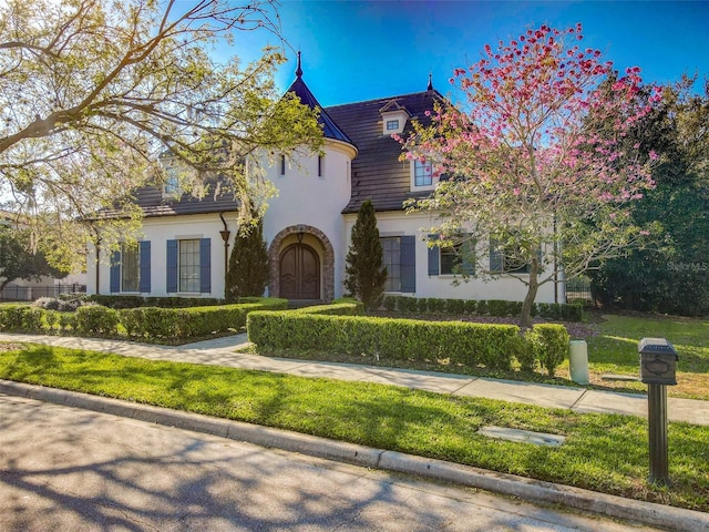 tudor house with a front lawn and stucco siding