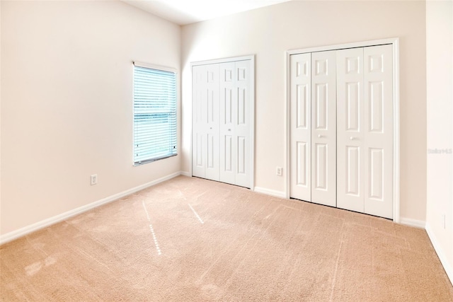 unfurnished bedroom with light carpet and two closets