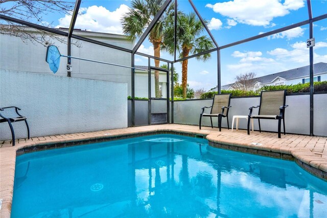 outdoor pool featuring a patio area and glass enclosure