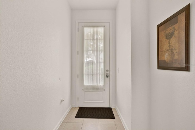 doorway with light tile patterned floors and baseboards