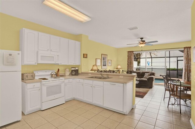 kitchen featuring a peninsula, white appliances, a sink, visible vents, and light countertops