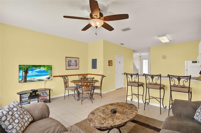 living area featuring light tile patterned floors, baseboards, visible vents, and electric panel