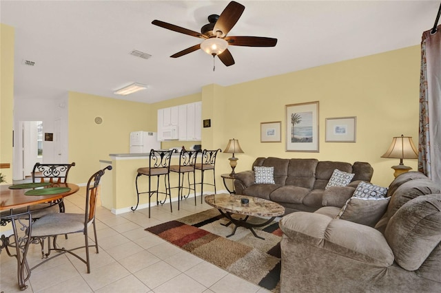 living area featuring light tile patterned floors, visible vents, and a ceiling fan