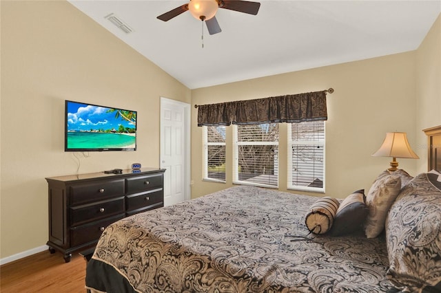 bedroom with baseboards, visible vents, a ceiling fan, lofted ceiling, and wood finished floors