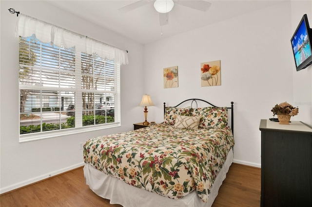 bedroom featuring wood finished floors, a ceiling fan, and baseboards