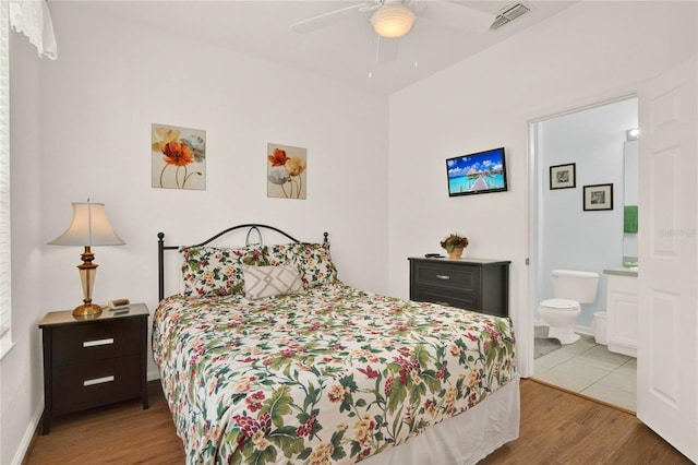 bedroom featuring baseboards, wood finished floors, visible vents, and connected bathroom