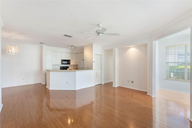 unfurnished living room featuring ceiling fan with notable chandelier and light hardwood / wood-style floors