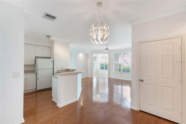 kitchen with white fridge, hanging light fixtures, white cabinetry, and light wood-type flooring