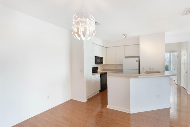 kitchen with white cabinets, decorative light fixtures, a kitchen island with sink, and black appliances