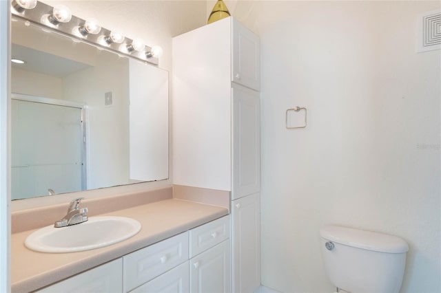 bathroom with toilet, a shower with shower door, and vanity