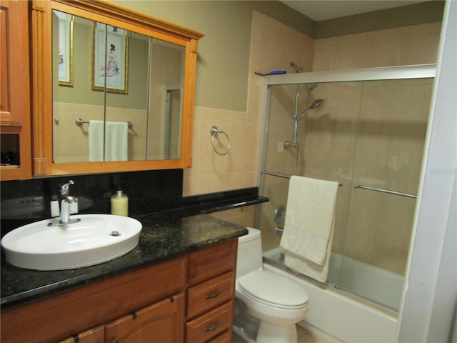 full bathroom featuring vanity, tile walls, shower / bath combination with glass door, and toilet