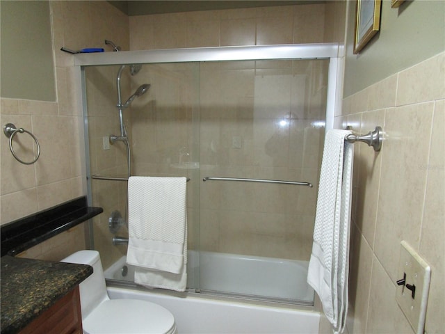 full bathroom with tile walls, vanity, enclosed tub / shower combo, and toilet