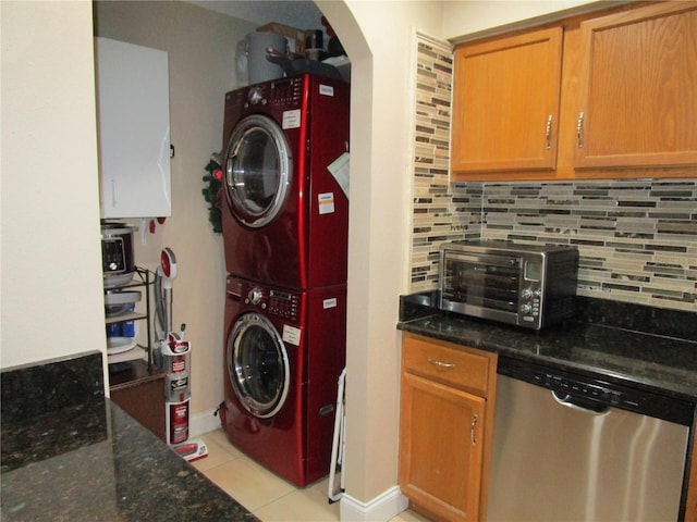 laundry room with stacked washing maching and dryer and light tile patterned floors