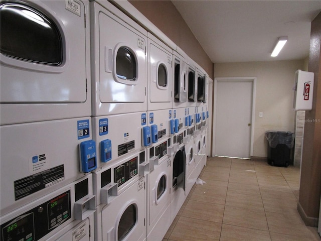 laundry room with stacked washer and dryer, light tile patterned floors, and washing machine and clothes dryer