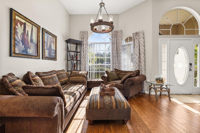 living room with wood-type flooring, a high ceiling, and a notable chandelier