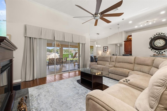 living room featuring ceiling fan with notable chandelier, dark wood-type flooring, and lofted ceiling