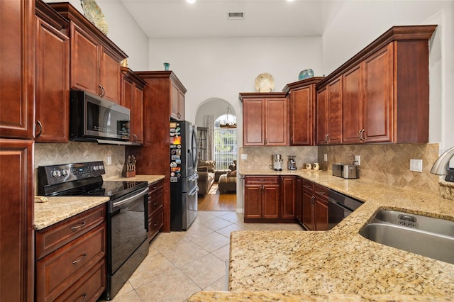 kitchen featuring light tile patterned flooring, sink, black appliances, and decorative backsplash