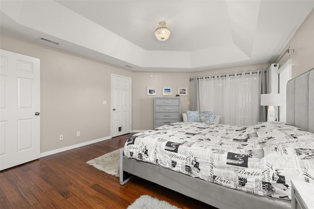 bedroom with dark wood-type flooring and a raised ceiling